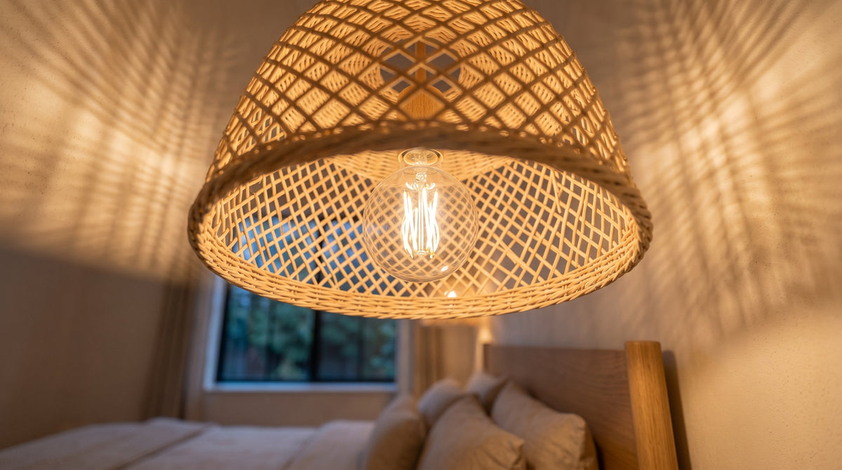 Ampoule LED à filament allumée dans un abat-jour en rotin tressé, ombres du tressage au plafond
