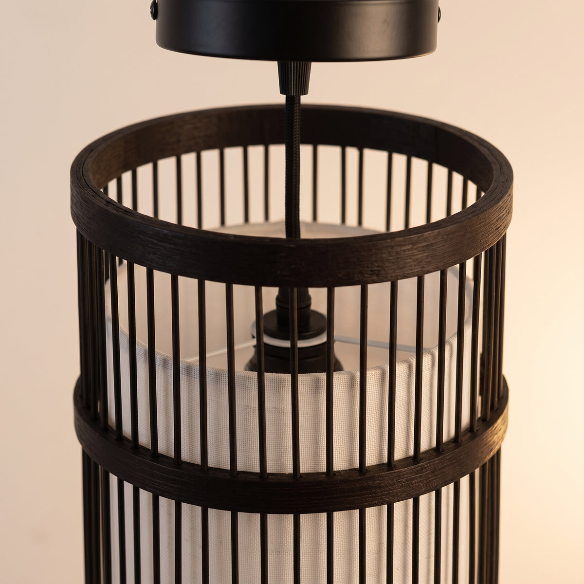 Gros plan sur le tressage et la finition : suspension en bambou cylindre noir