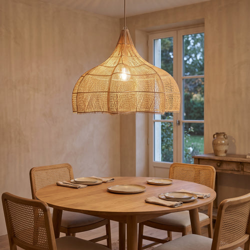Grande suspension en rotin forme citrouille allumée le soir dans un grand salon japandi